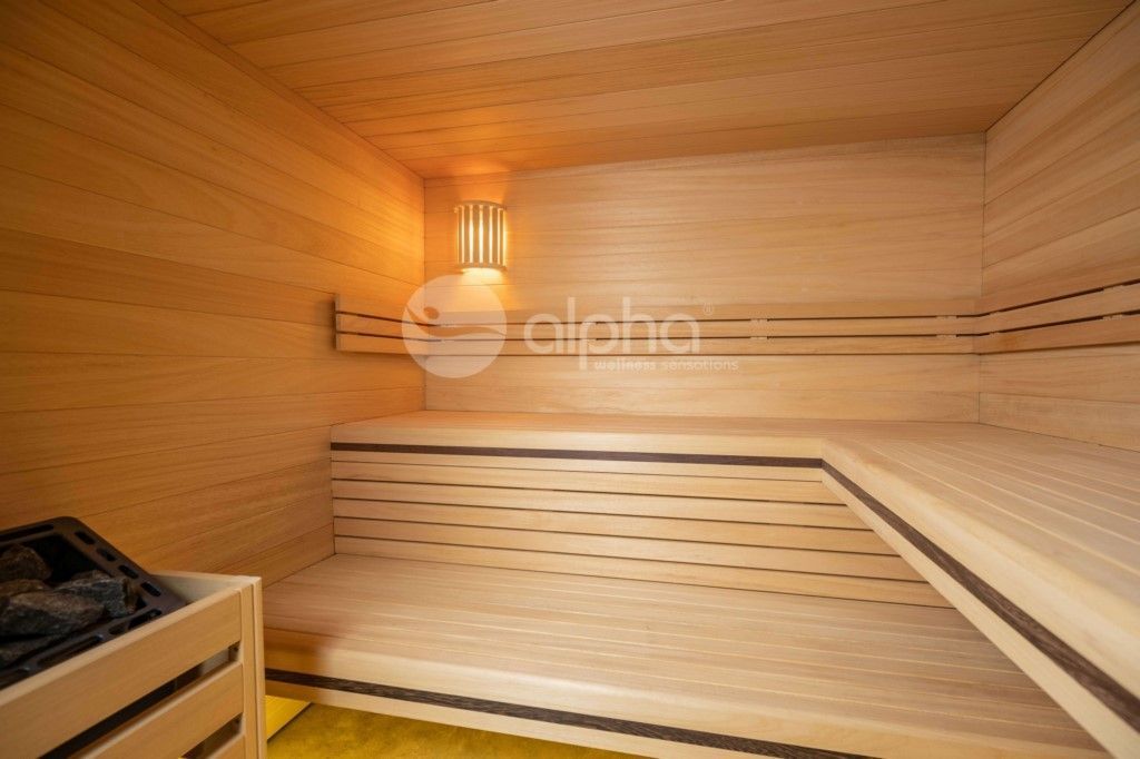 Un sauna en bois avec un poêle et une lampe au mur.