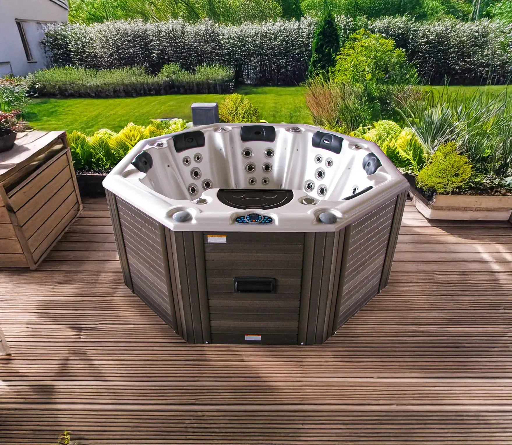 Un jacuzzi octogonal sur une terrasse en bois, entouré de verdure. Le jacuzzi est gris avec un intérieur clair.