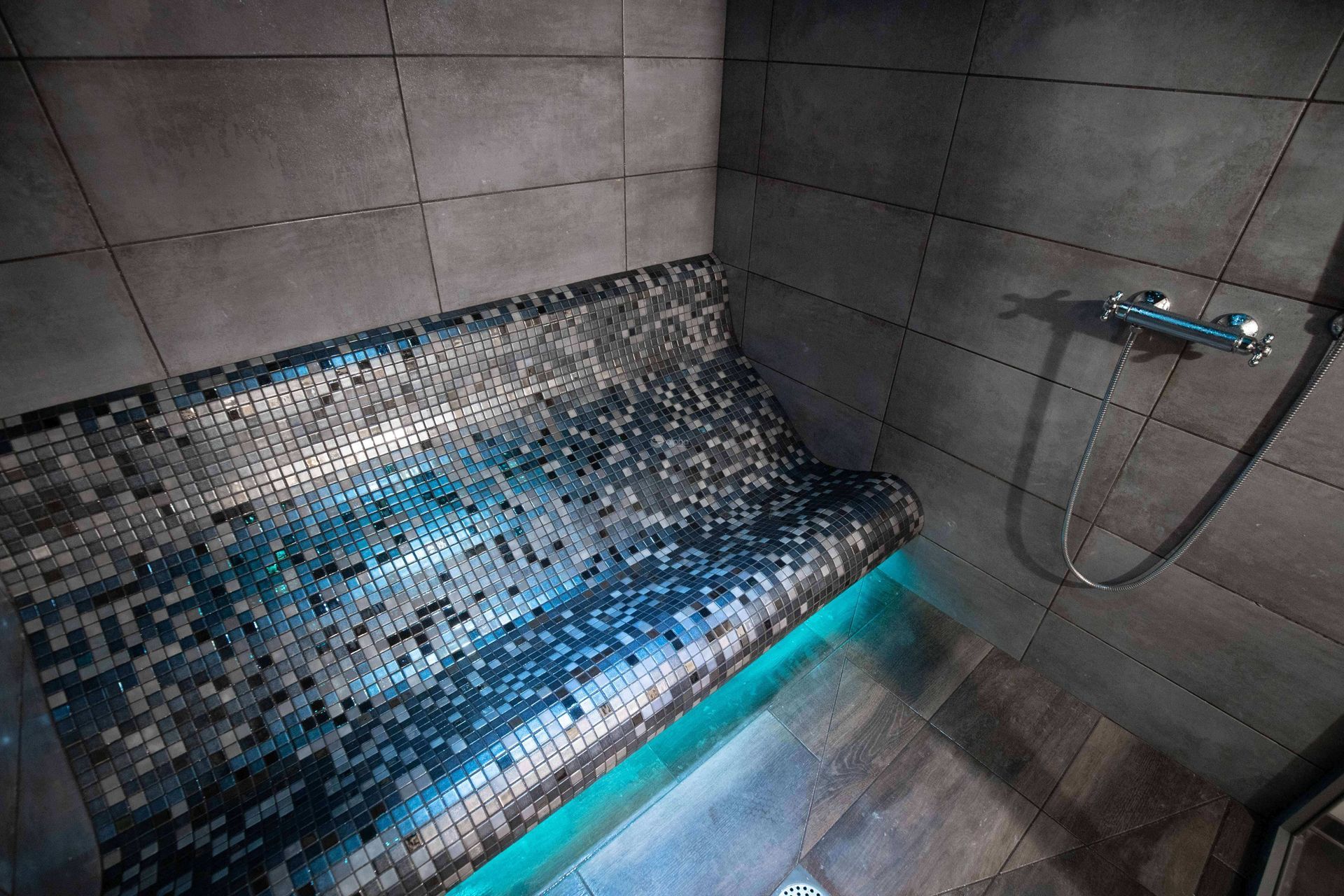 Il y a un banc dans la douche hammam avec une pomme de douche.