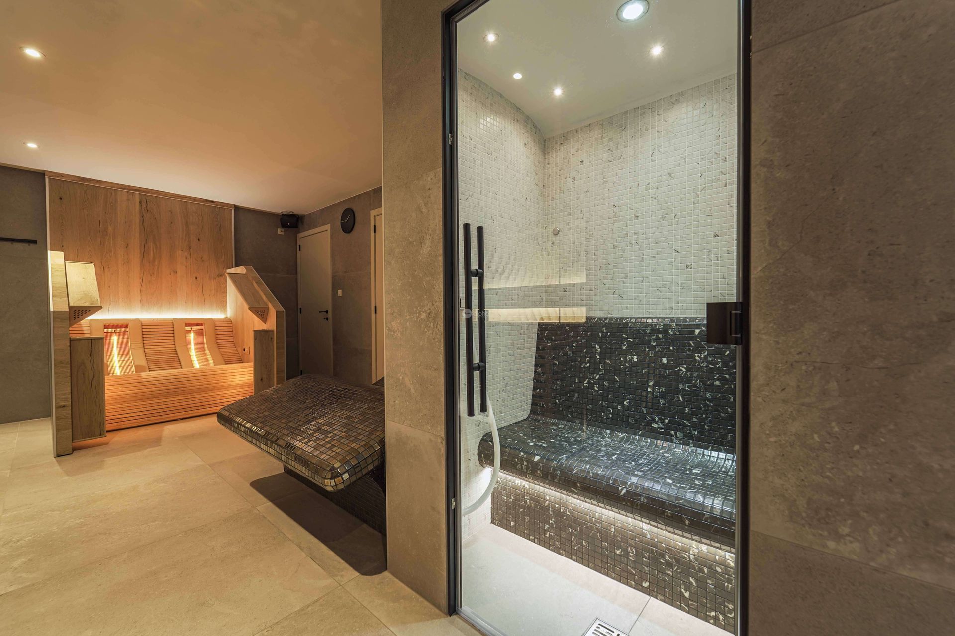 Une pièce hammam avec une porte vitrée et un banc à l'intérieur.