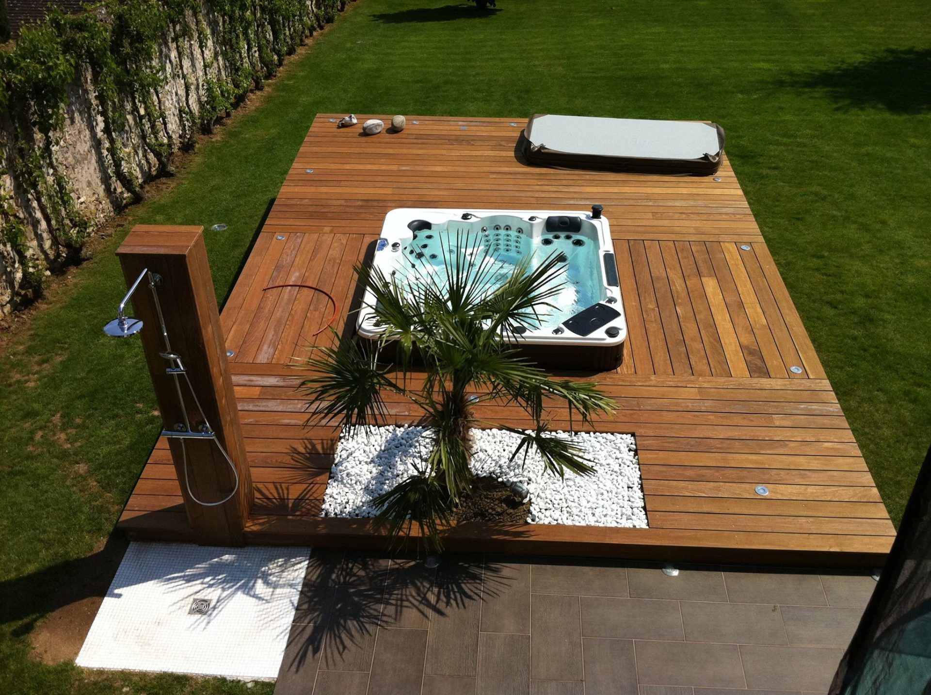 Une terrasse en bois avec un jacuzzi et un palmier