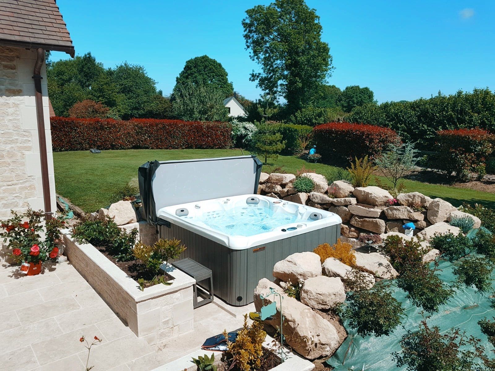 Un jacuzzi est installé au milieu d'un jardin à côté d'une maison.