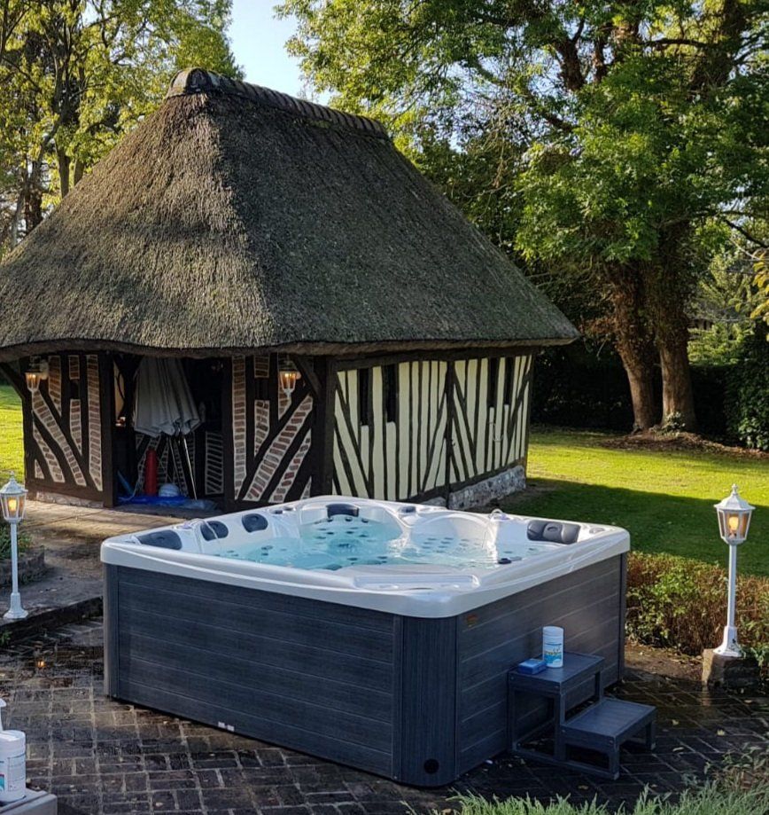 Un kiosque au toit de chaume avec un bain à remous devant