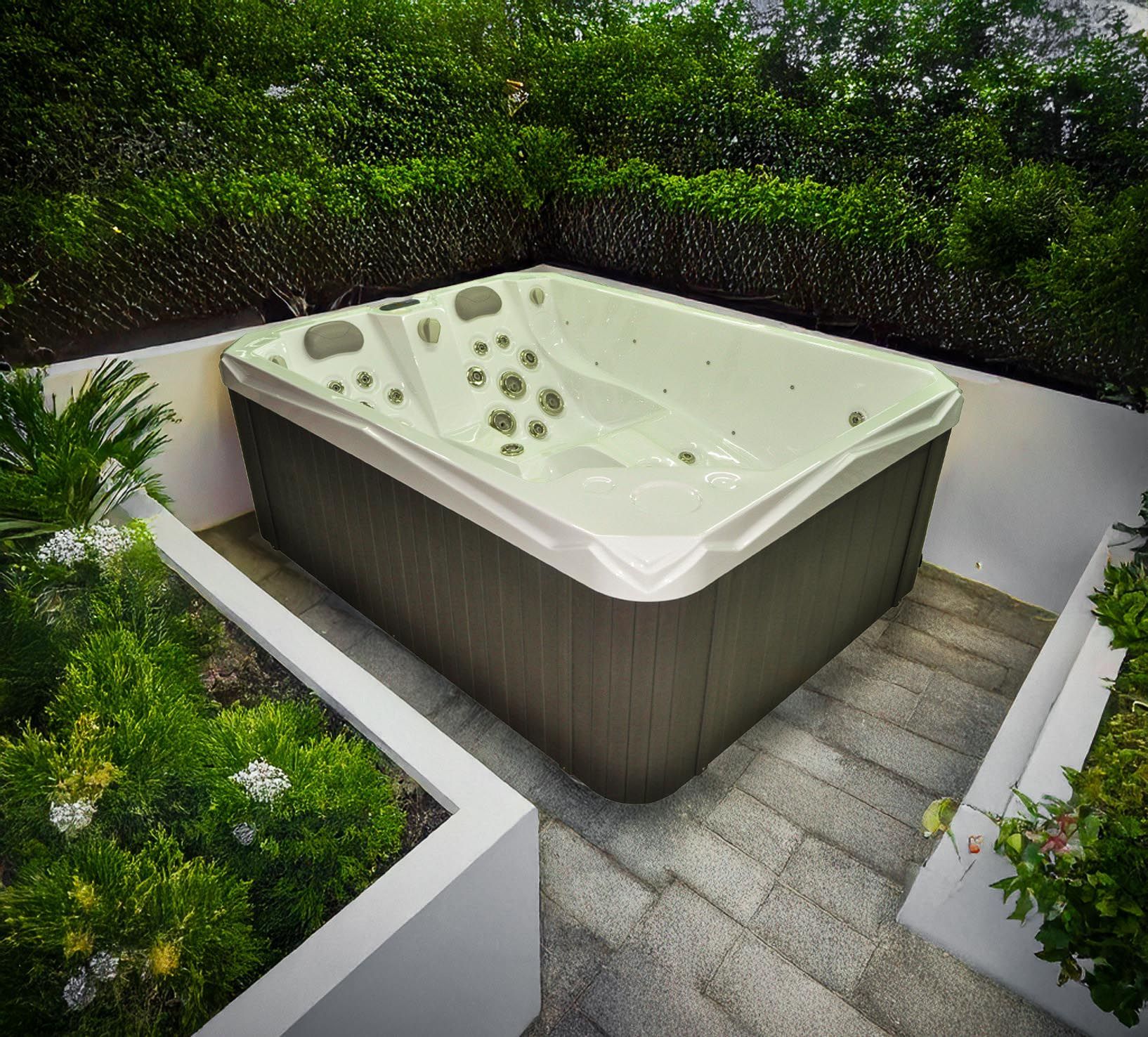 Spa situé dans un patio en retrait, entouré de verdure et d'un escalier en pierre. Rectangulaire, il est équipé de jets et présente un intérieur blanc.