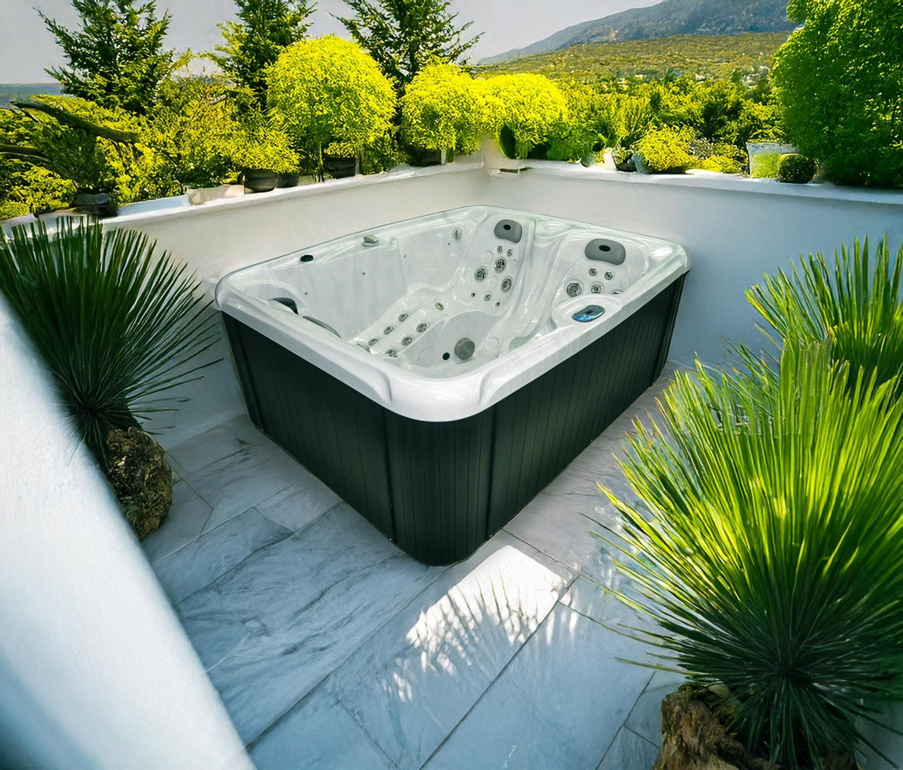 jacuzzi entouré de plantes vertes sur une terrasse blanche, sur fond de feuillage et de montagnes.