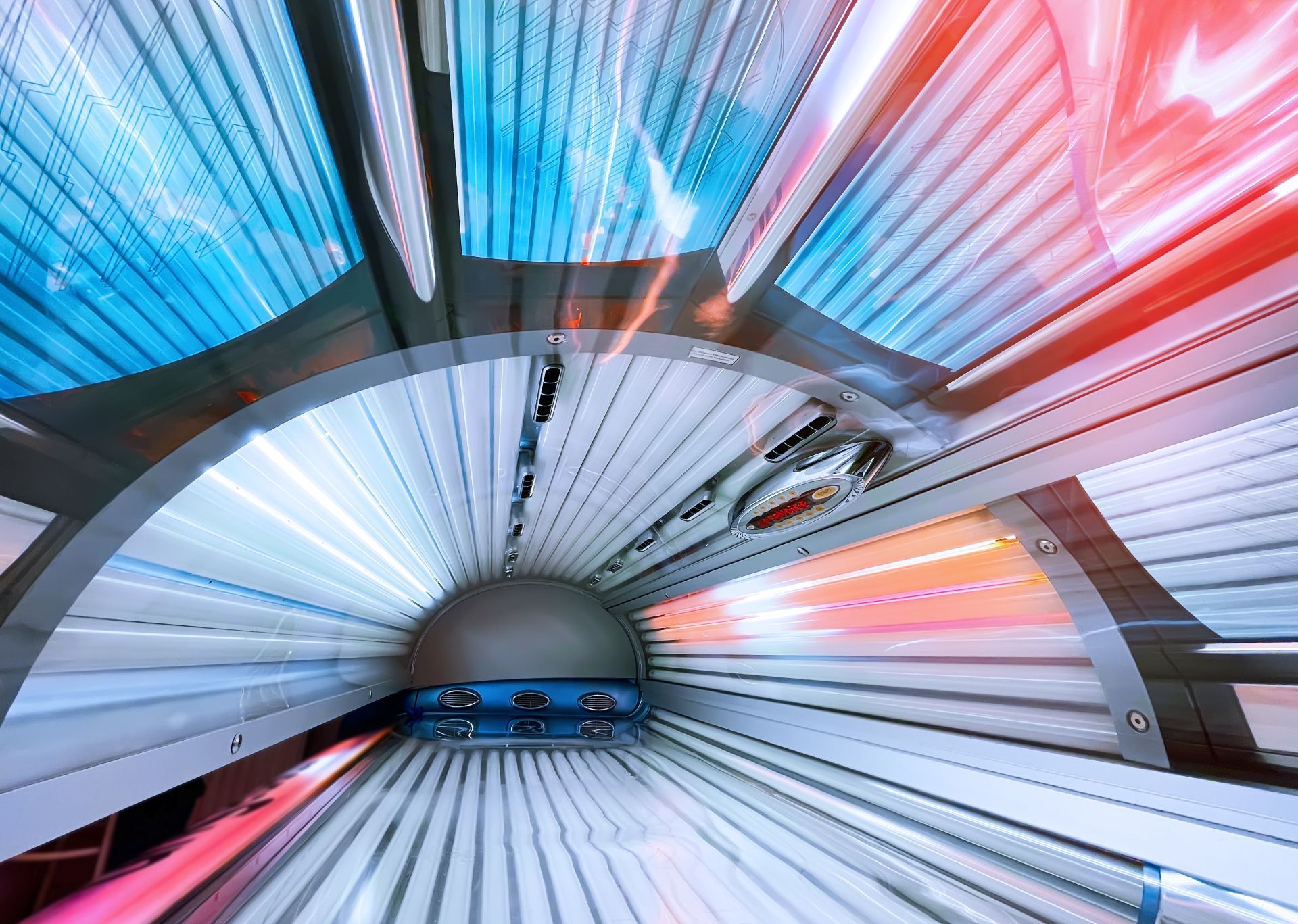 Inside of a tanning bed with vibrant blue and red lights.