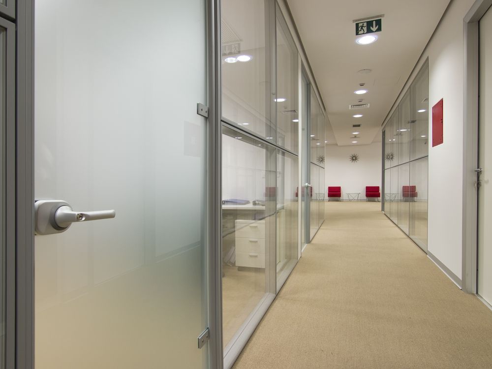 Office Hallway With Glass-walled Rooms, Beige Carpet, and Red Chairs in the Distance — Working Windows in Lennox Head, NSW