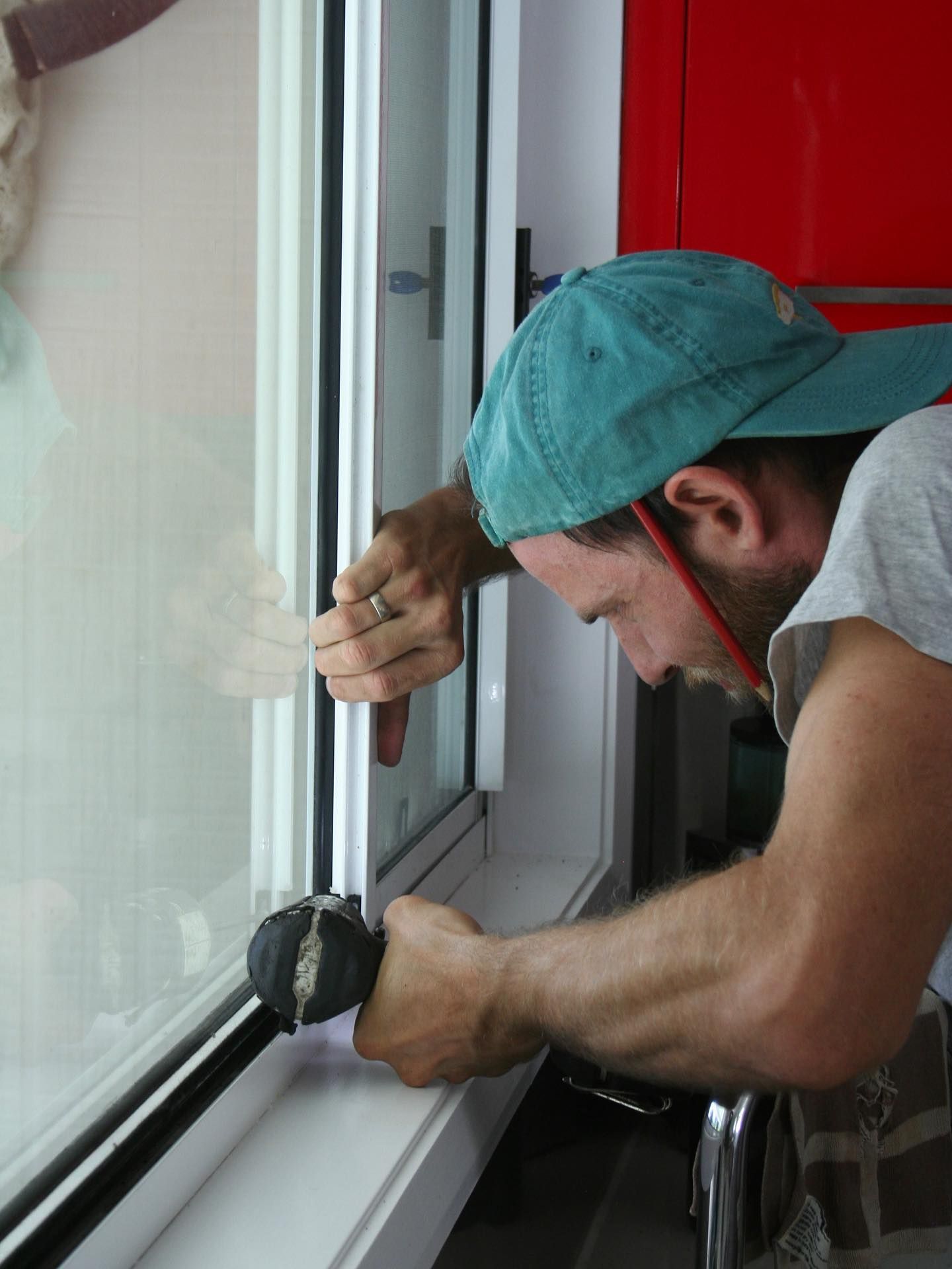 Person in a Blue Cap Sealing a Window Frame With a Caulking Gun — Working Windows in Byron Bay, NSW
