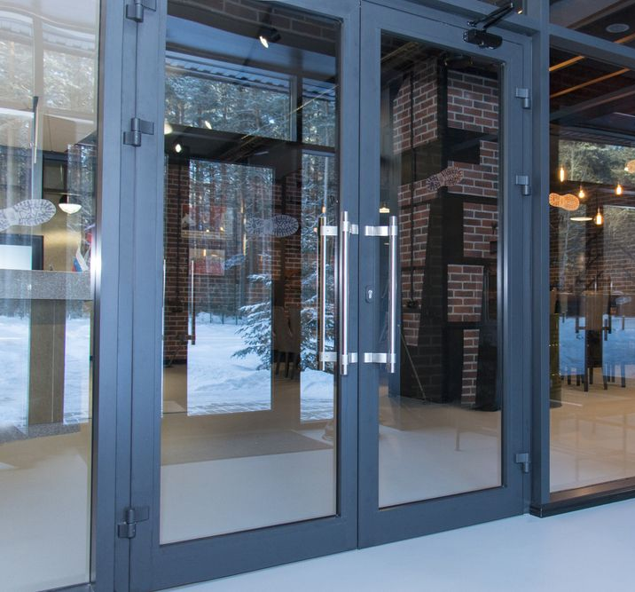 A double glass door with dark metal frames, stainless steel handles, and a brick interior visible through the glass — Working Windows in Ocean Shores, NSW