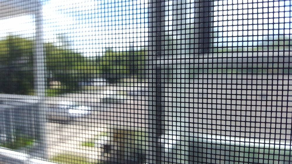 Person Installing a White Screen in a Window on a Brick Building — Working Windows in Mullumbimby, NSW