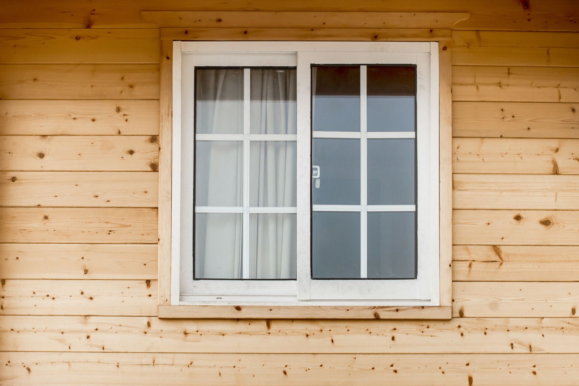 White-framed Sliding Window With a Grid Pattern on a Light-colored Wood Exterior — Working Windows in Ocean Shores, NSW
