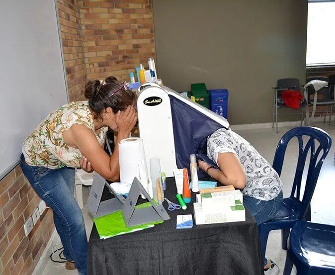 Una mujer cubriéndose la cara mientras otra mujer está sentada en una mesa.