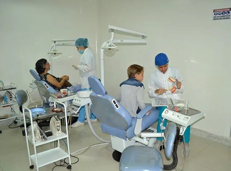 Un grupo de personas están sentadas en sillas dentales en un consultorio dental.