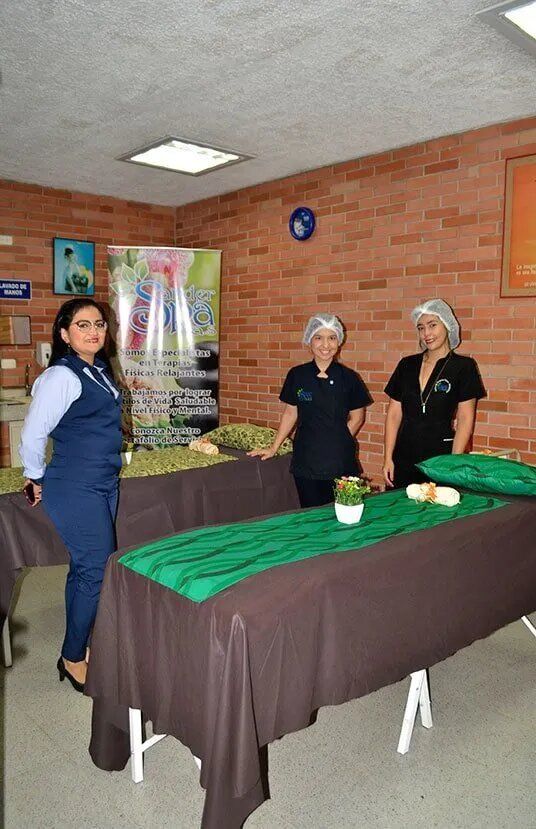 Tres mujeres están de pie alrededor de una mesa con un mantel verde encima.