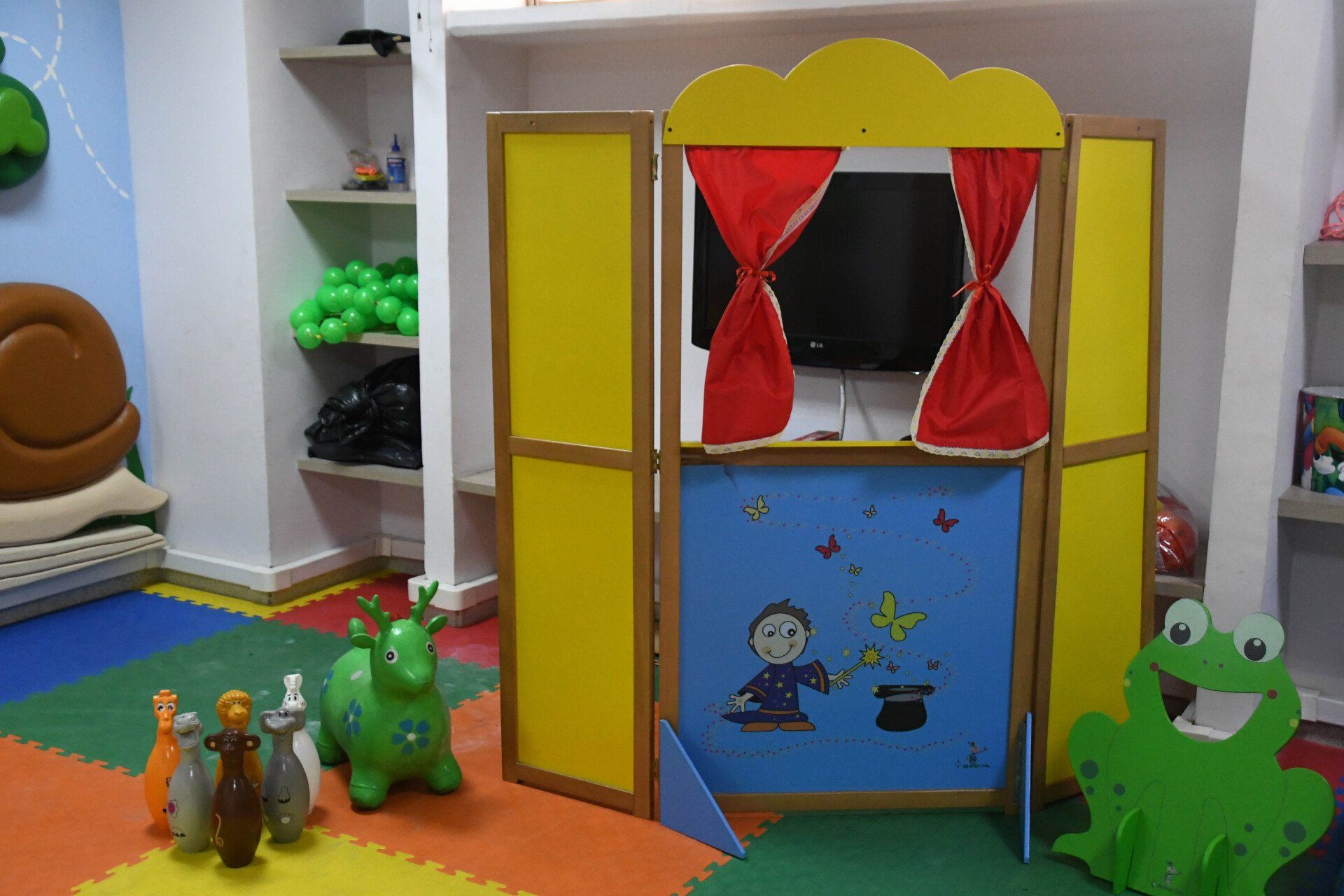 Una sala infantil con teatro de marionetas y bolos.