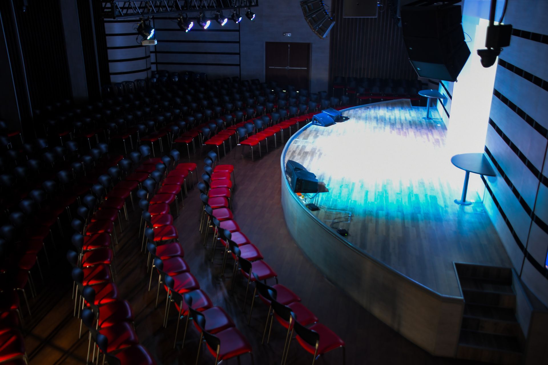Un auditorio vacío con asientos rojos y un escenario.