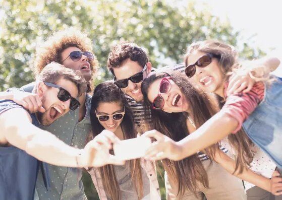 Un grupo de jóvenes que llevan gafas de sol se están tomando un selfie.