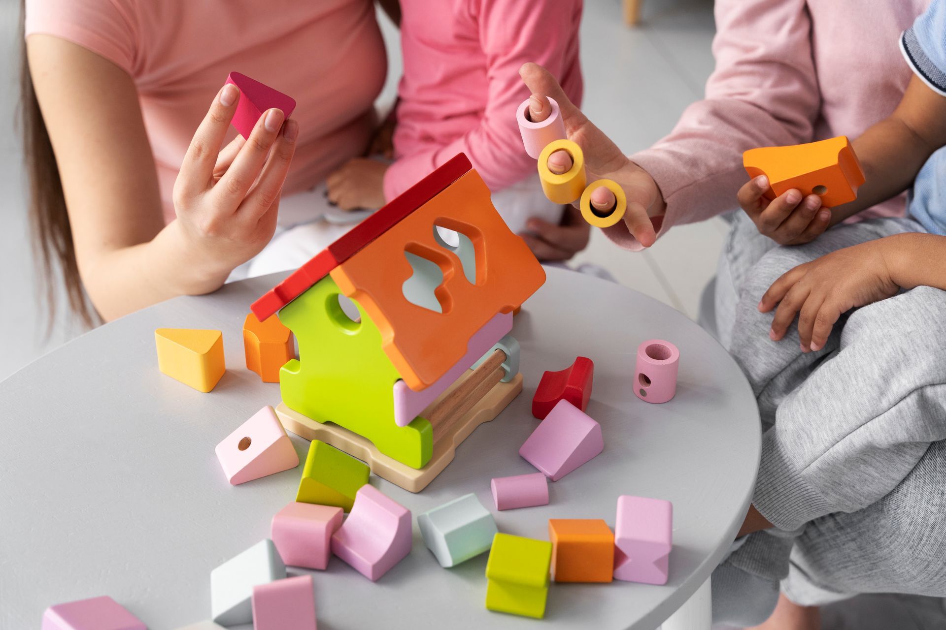 Un grupo de niños está sentado en una mesa jugando con bloques de madera.