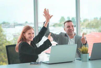 Un hombre y una mujer se chocan los cinco frente a una computadora portátil.
