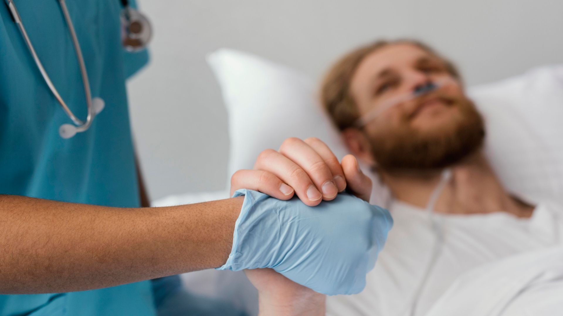 Un médico sostiene la mano de un paciente en una cama de hospital.