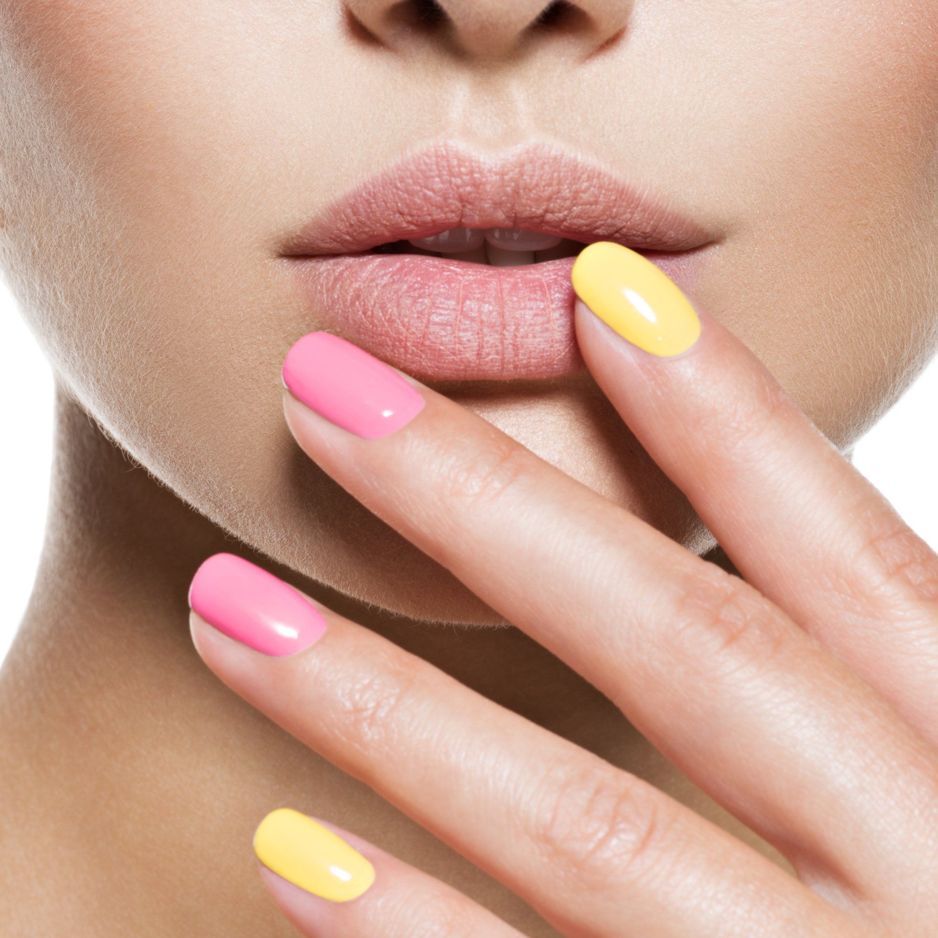 Un primer plano del rostro de una mujer con uñas rosas y amarillas.