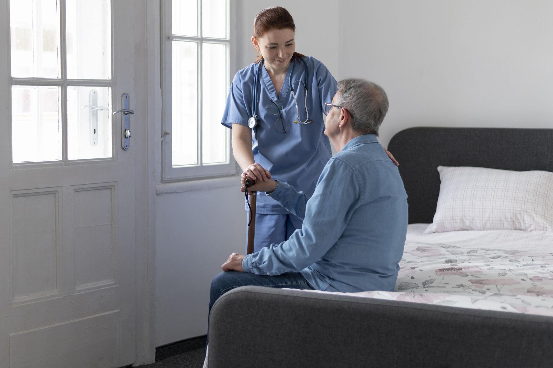 Un médico sostiene la mano de un paciente en una cama de hospital.