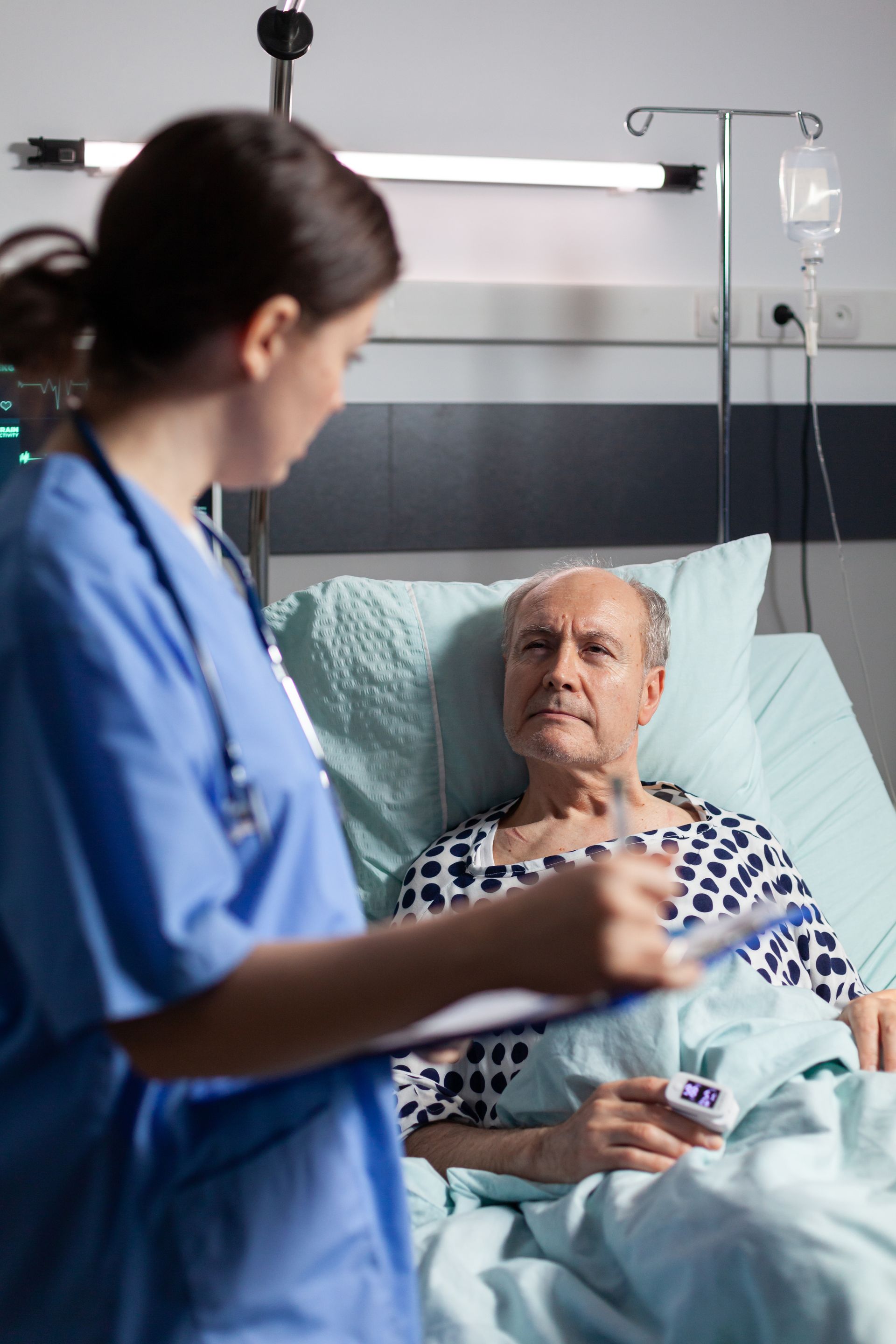 Una enfermera está hablando con un paciente en una cama de hospital.