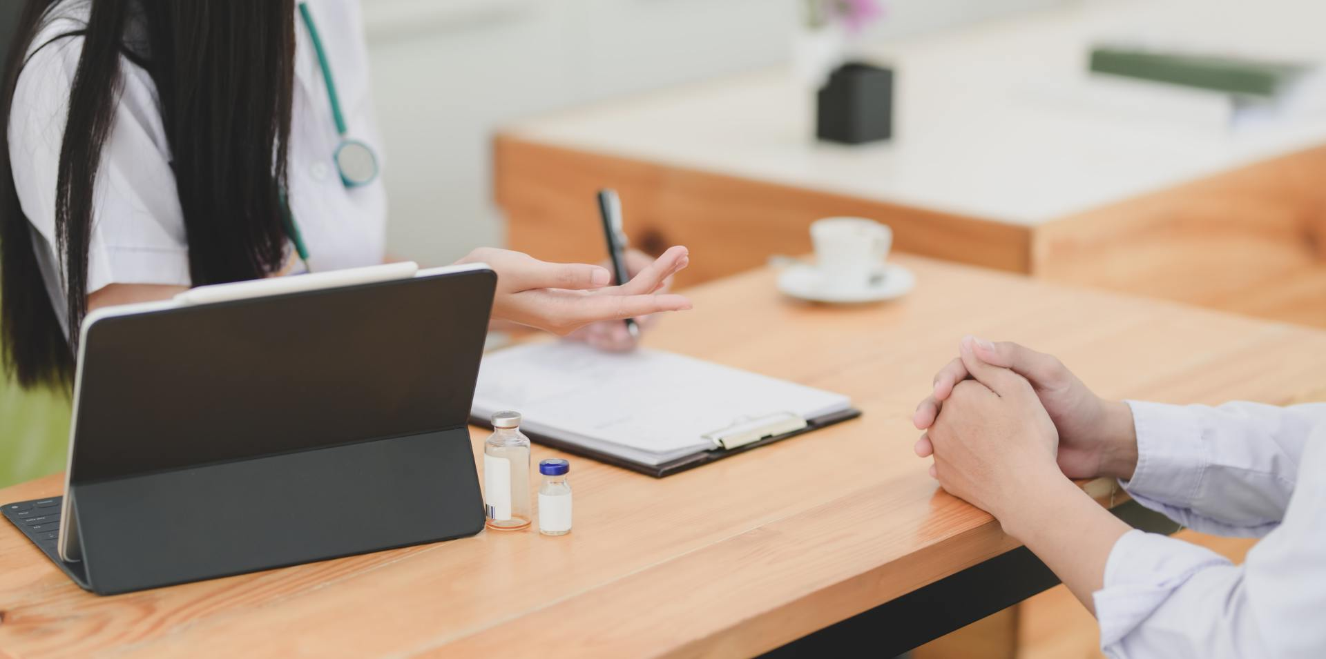 Un médico está sentado en una mesa hablando con un paciente.