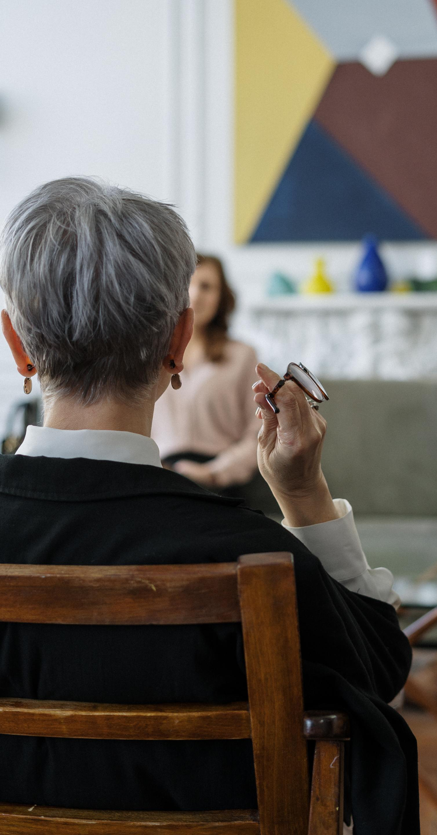 Un hombre está sentado en una silla sosteniendo un par de gafas.