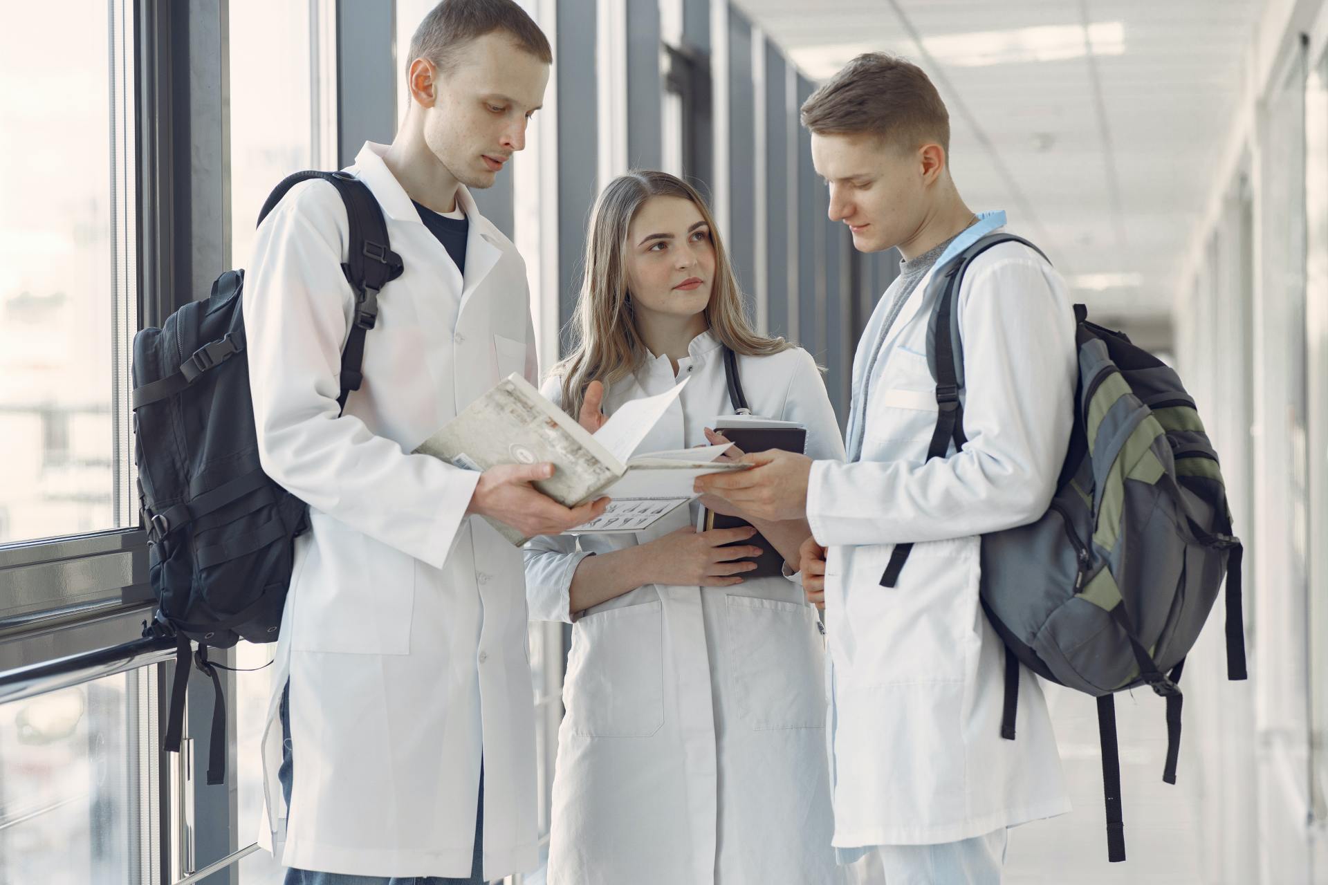 Un grupo de estudiantes de medicina está de pie en un pasillo mirando un libro.