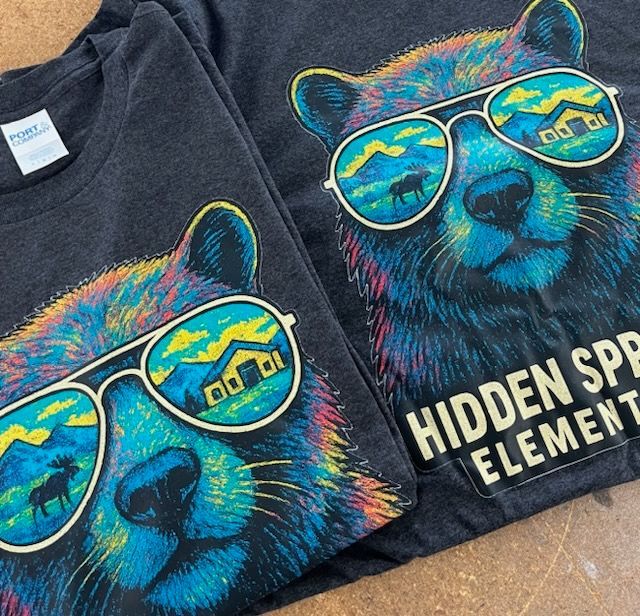 Two gray t-shirts with a colorful bear wearing sunglasses. One says 