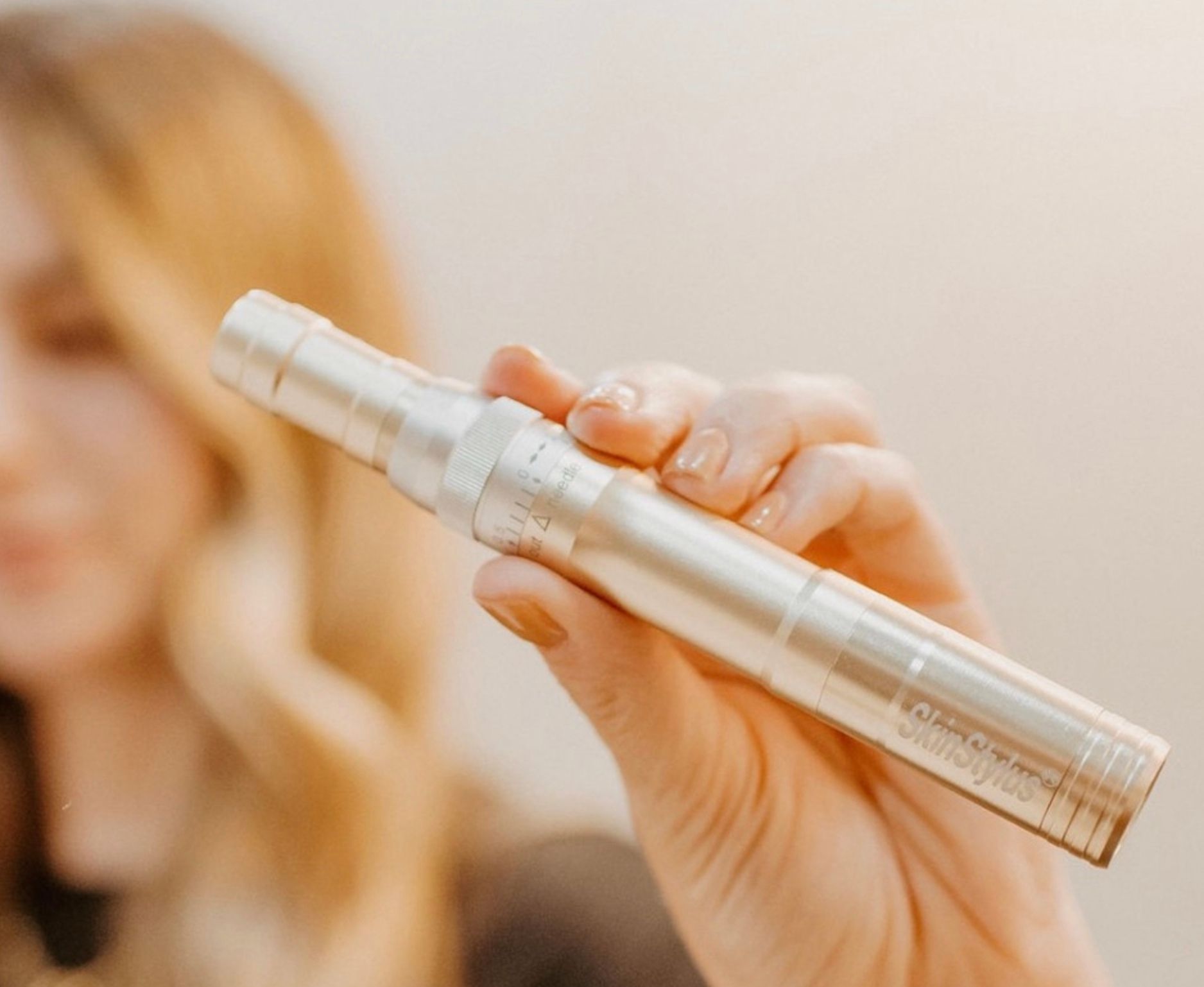 A woman is holding a silver pen in her hand.