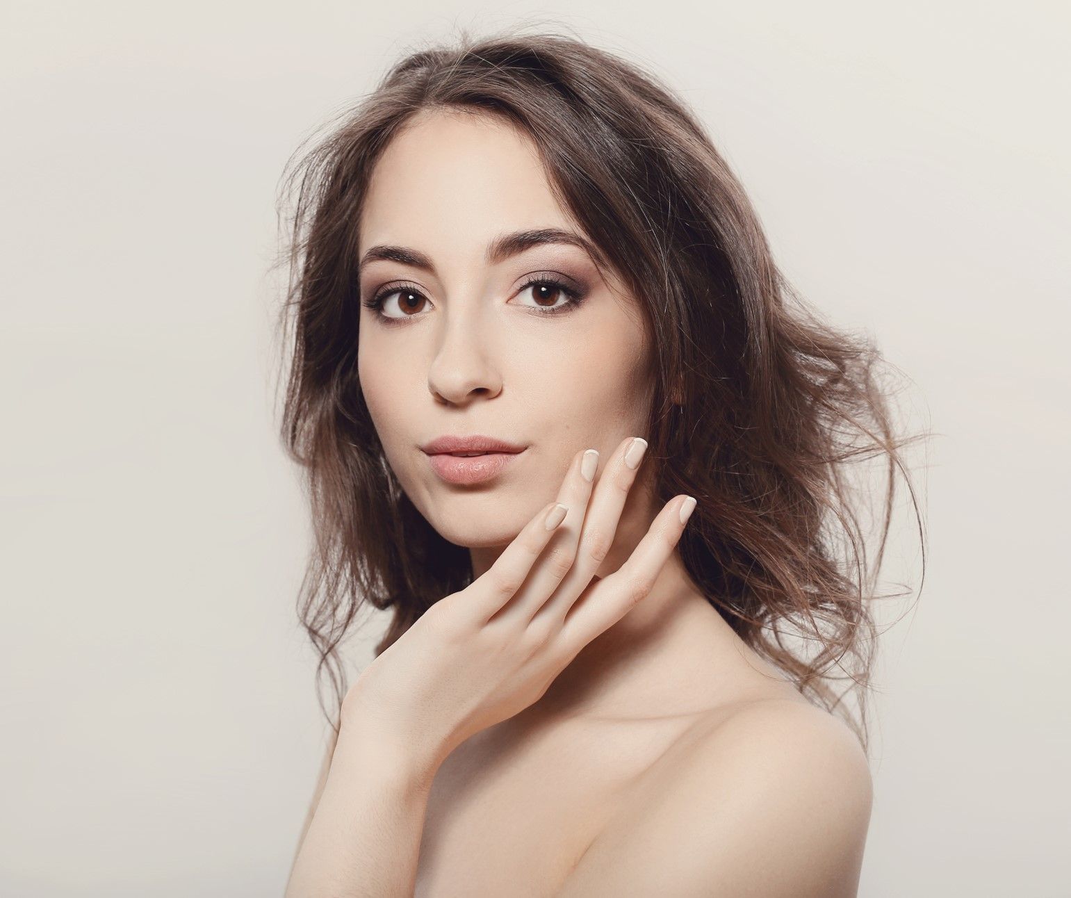 A woman is touching her face with her hand and looking at the camera.