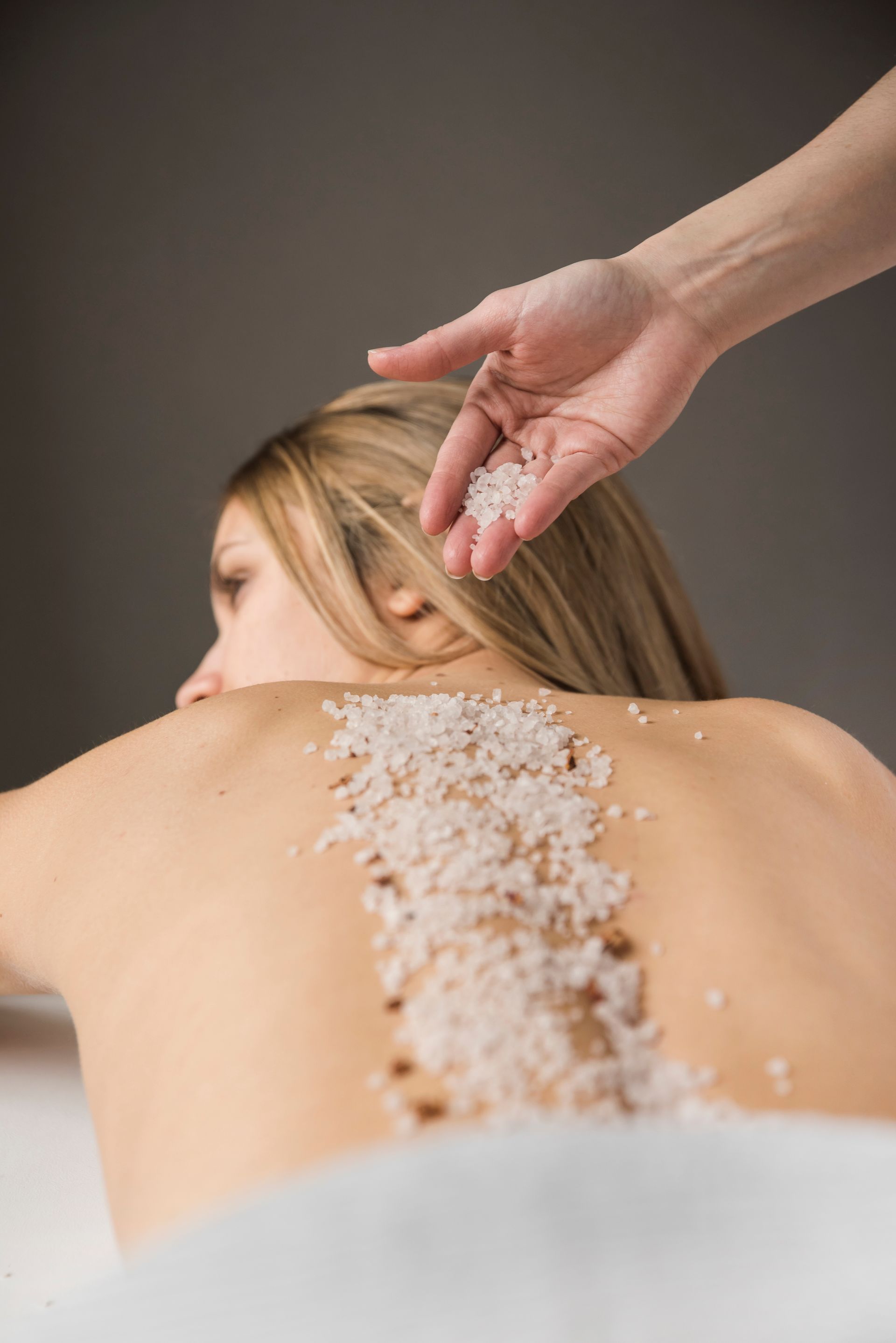 A woman is getting a massage with sea salt on her back.