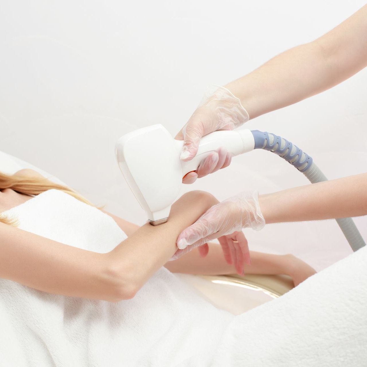 A woman is getting a hair removal treatment on her arm