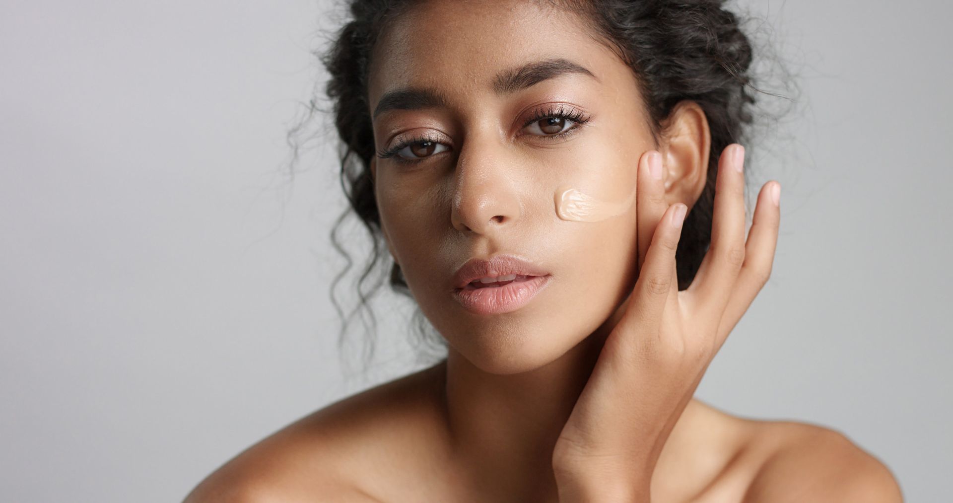 A woman is applying foundation to her face.