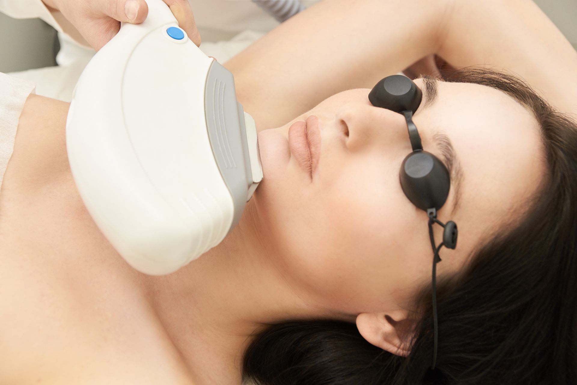 A woman is getting a laser hair removal treatment on her face.