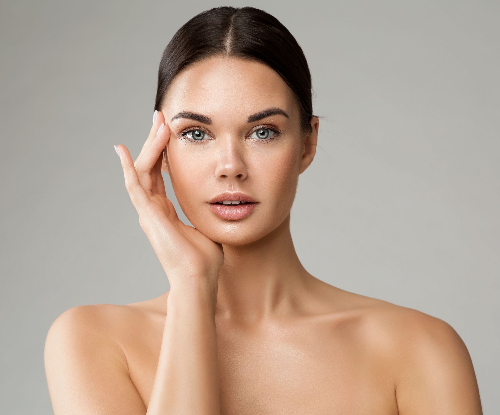 A woman is touching her face with her hand and looking at the camera.