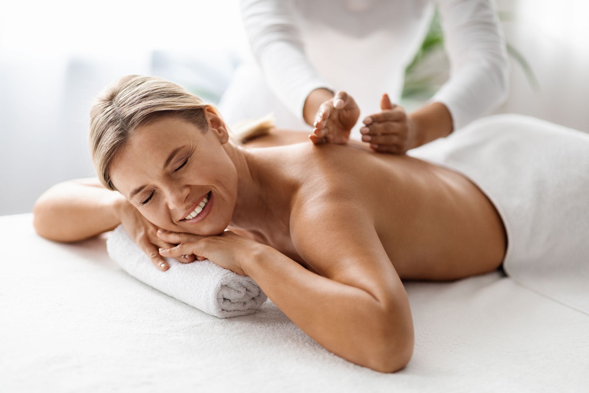 A woman is smiling while getting a massage at a spa.