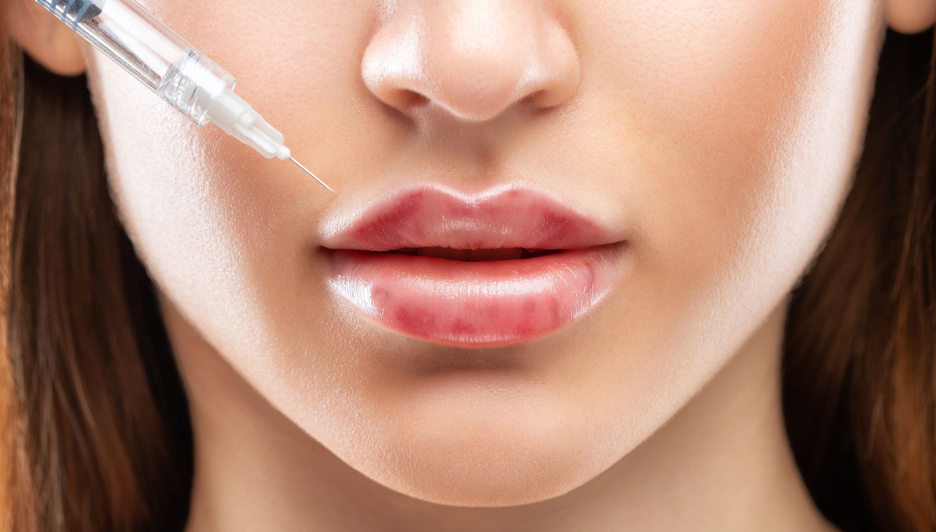 A woman is getting a botox injection in her lips.