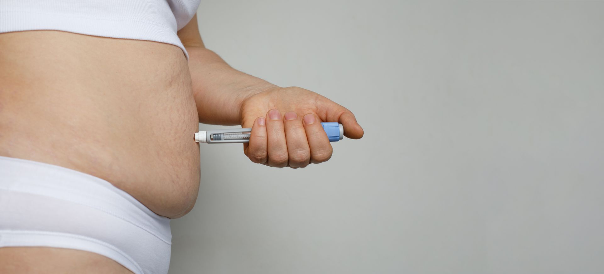 A woman is injecting herself with an insulin pen.