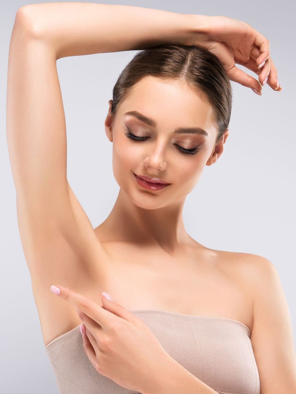 A woman is applying lotion to her armpit.