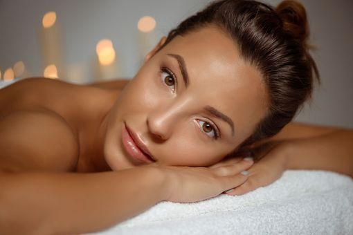 A woman is laying on a massage table with her head on a towel.