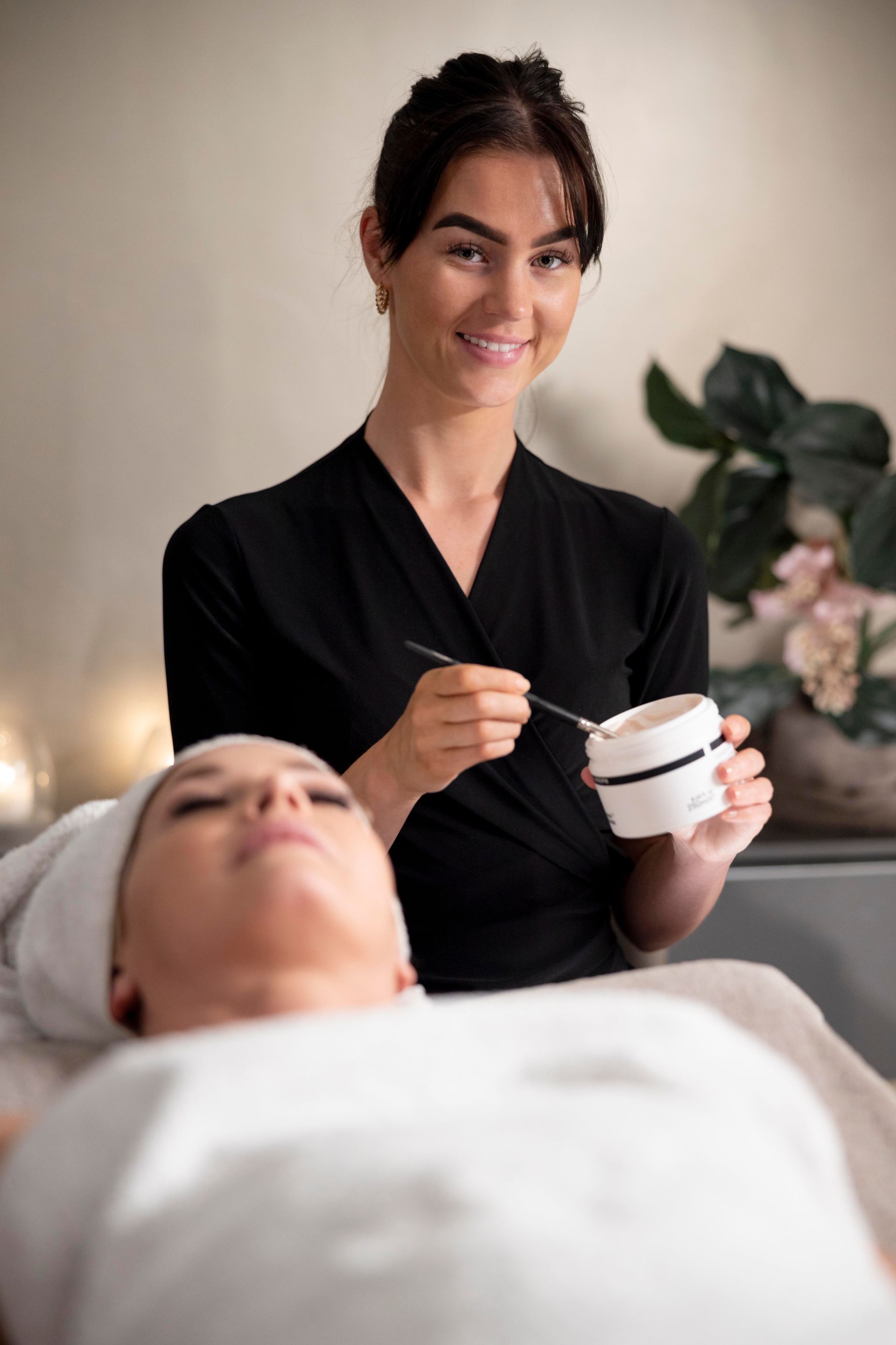 A woman is applying a cream to a woman 's face in a spa.