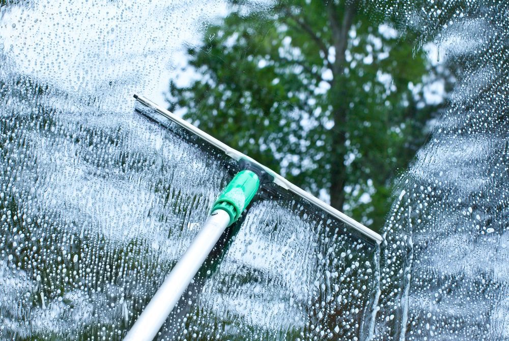 A person is cleaning a window with a squeegee.