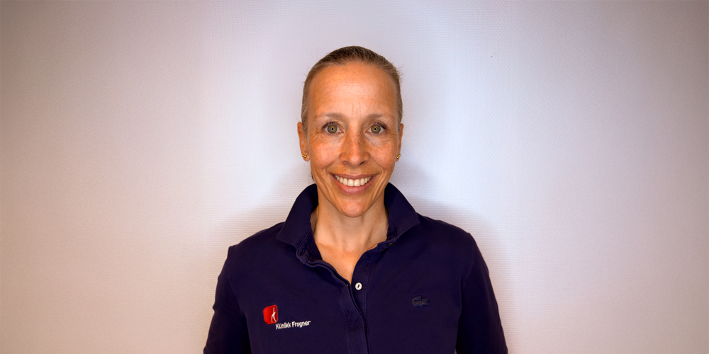 Kvinne som bokser i et treningsstudio og slår med en tung boksesekk. Hun har på seg hansker og sports, med fokusert uttrykk.