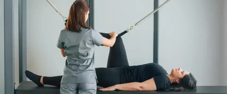 Kvinne som mottar fysioterapi, beinet strukket med stropper av en helsepersonell.