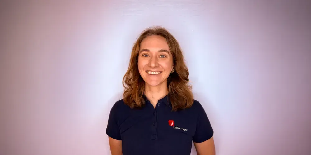 En kvinne ligger på et massasjebenk og får fysioterapi. En person i grå behandler beinet hennes.