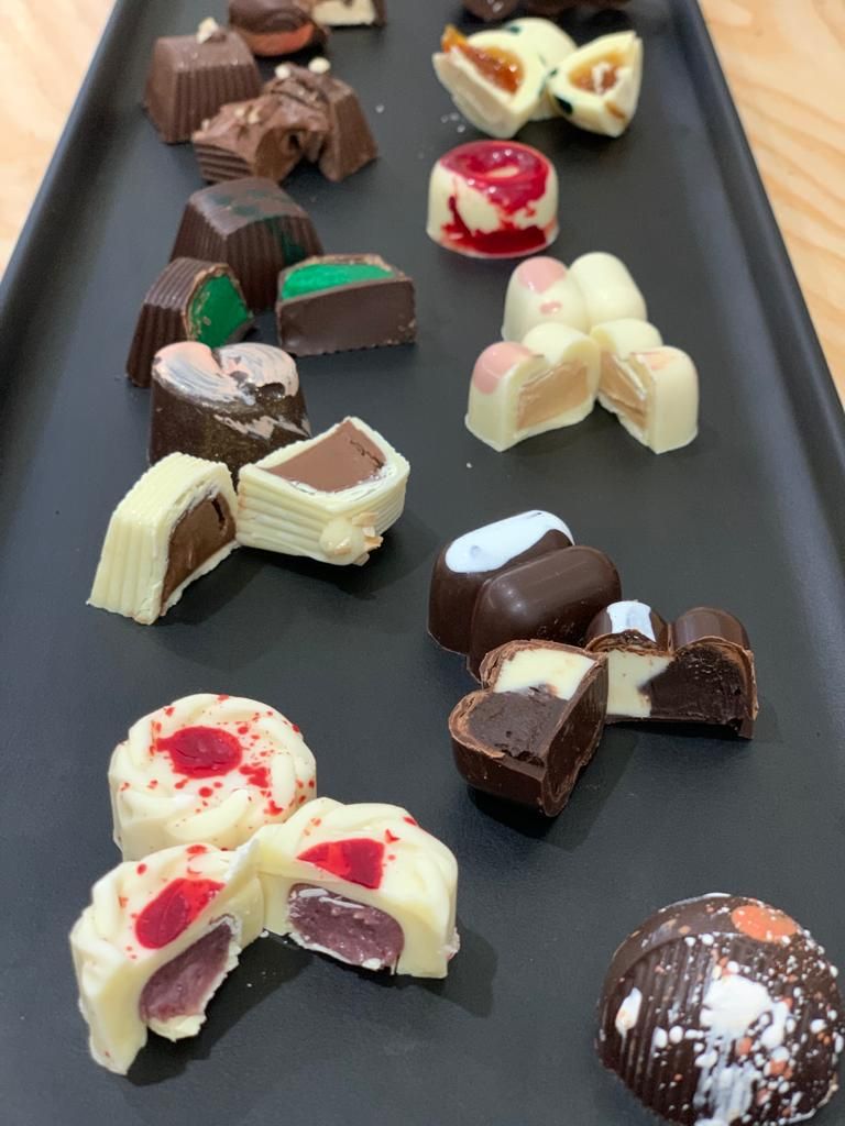 Tartufi di cioccolato assortiti e cioccolatini ripieni disposti su un vassoio scuro