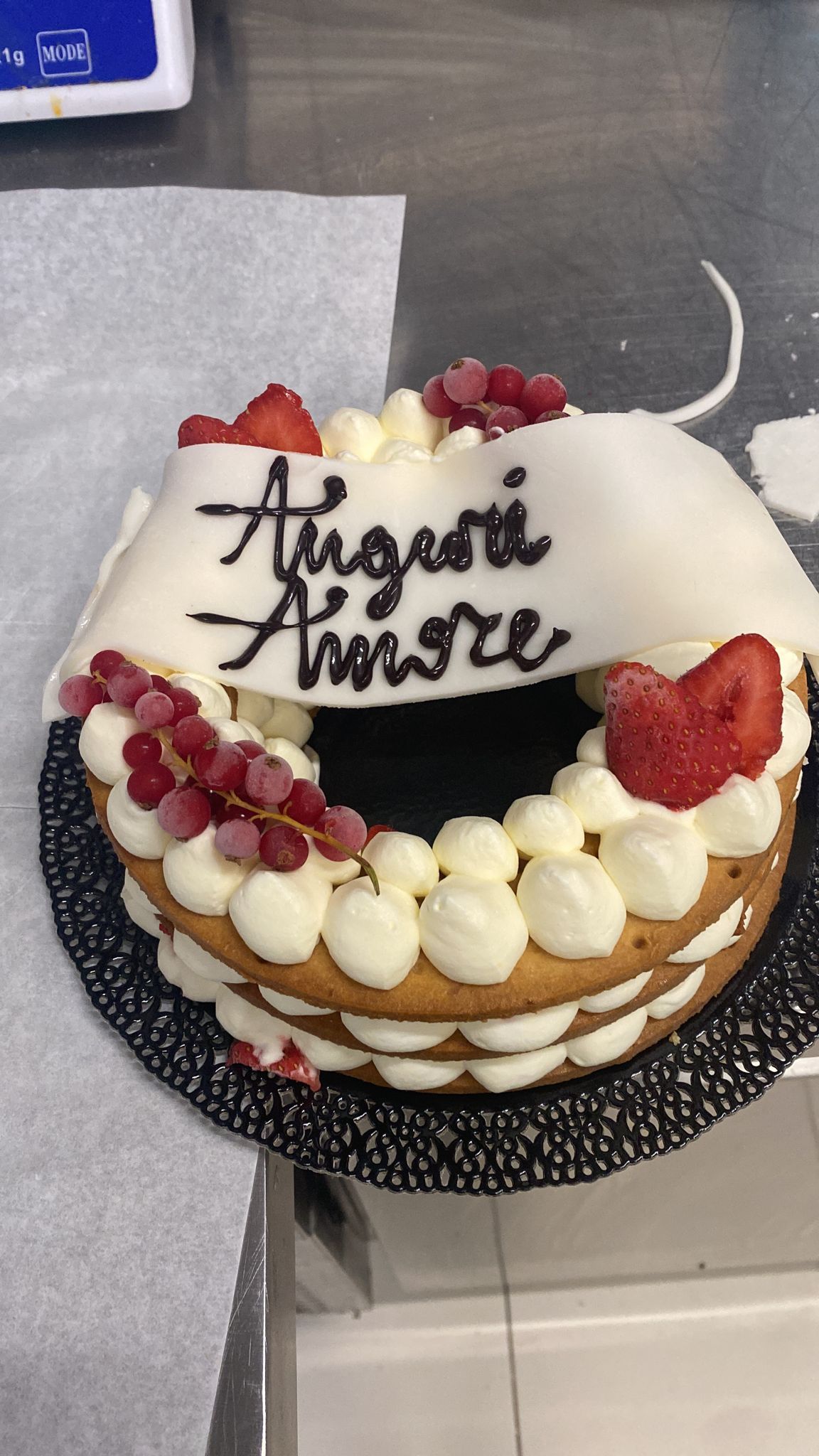 Torta con glassa bianca, frutti di bosco e crema pasticcera su un vassoio scuro, decorata con